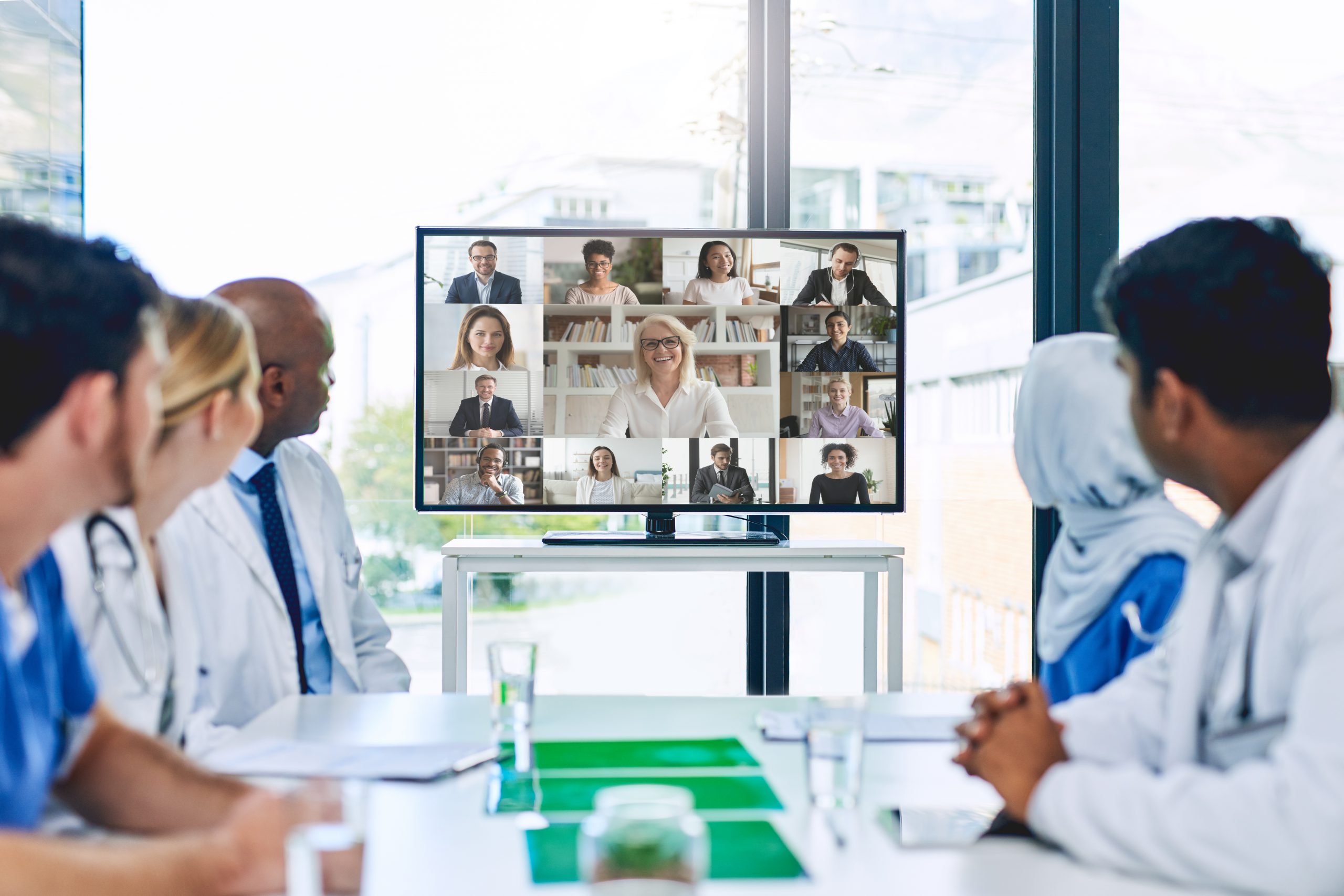 doctors and nurses watch a tv screen showing ECHO sessions