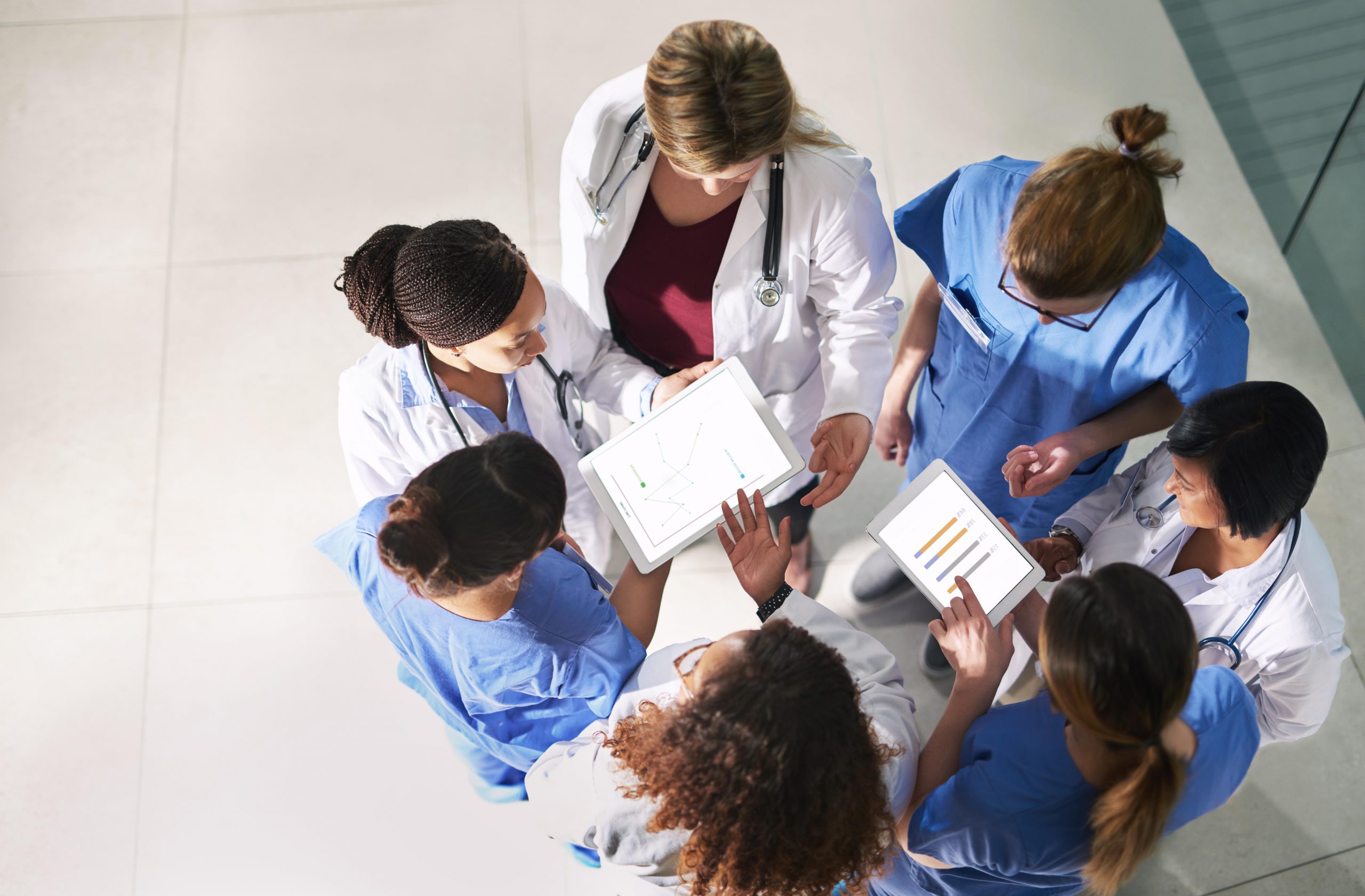 a group of doctors and nurses standing in a circle, discussing their notes